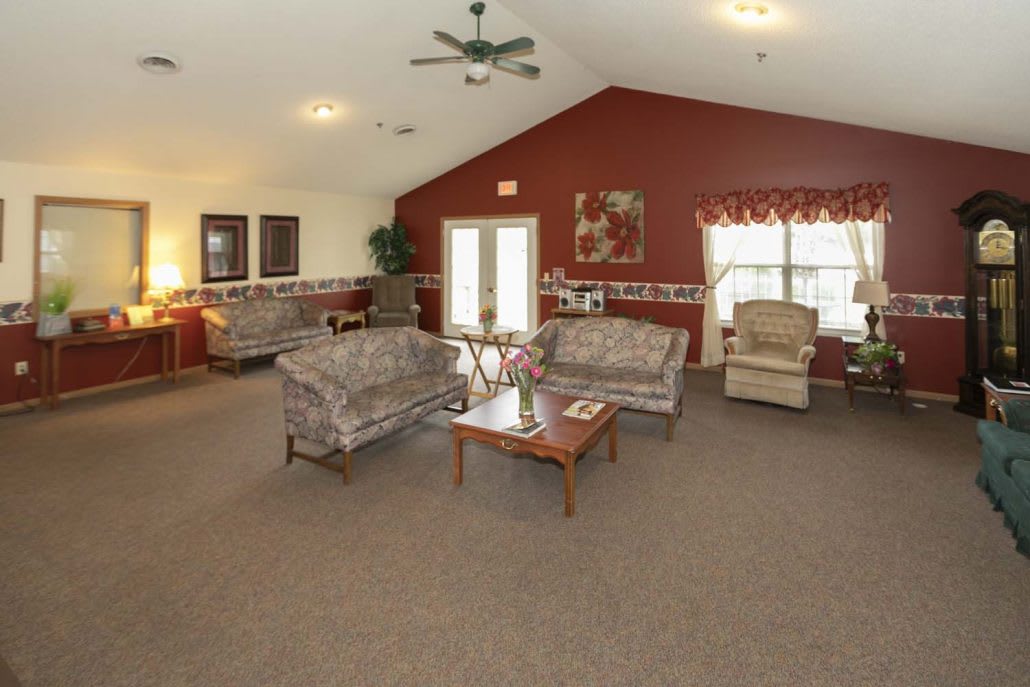 A spacious living room with sofas, tables, and a ceiling fan.