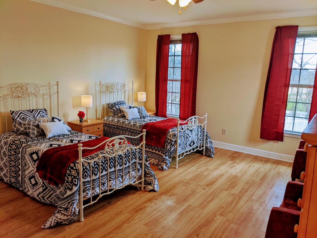 A cozy bedroom with twin beds, red accents, and warm lighting.