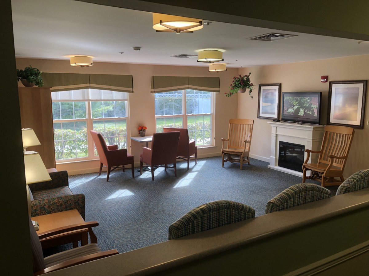 A cozy living room with chairs and a fireplace, featuring large windows and ample natural light.