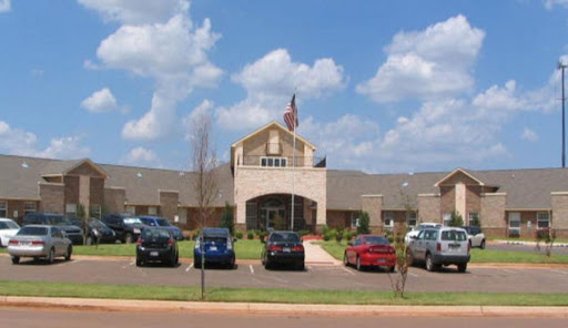 A view of a building with an American flag in front and cars parked in the lot.