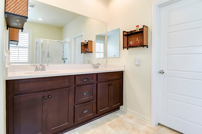 A modern bathroom featuring a wooden vanity with a large mirror and sink.