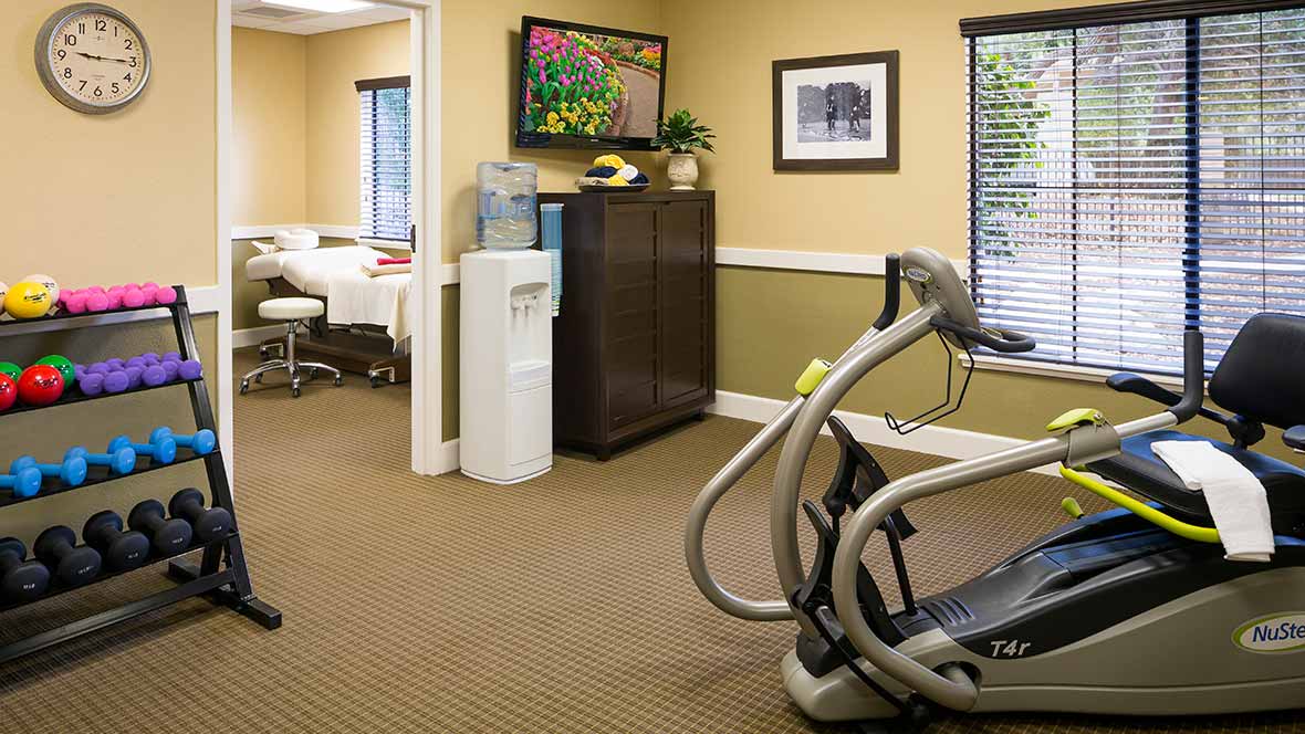 A small gym area with exercise equipment, a water cooler, and office furniture.