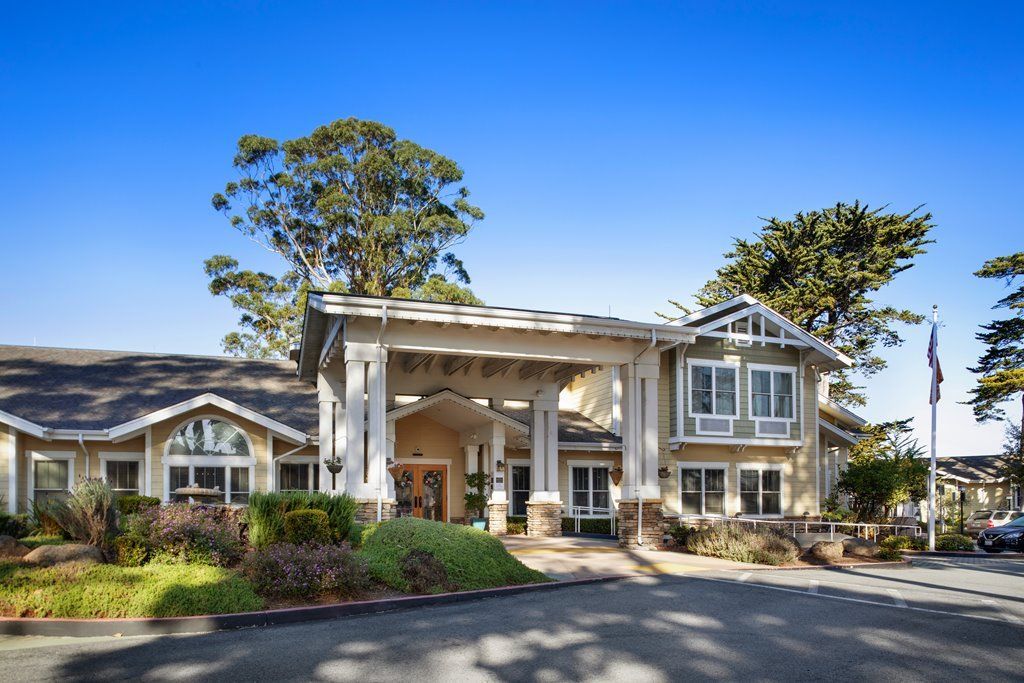 A picturesque building with a welcoming entrance, surrounded by lush greenery and clear blue skies.