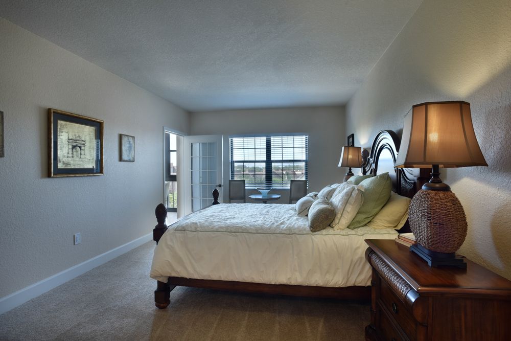 A spacious and elegantly decorated bedroom with a comfortable bed, large windows, and stylish furnishings.