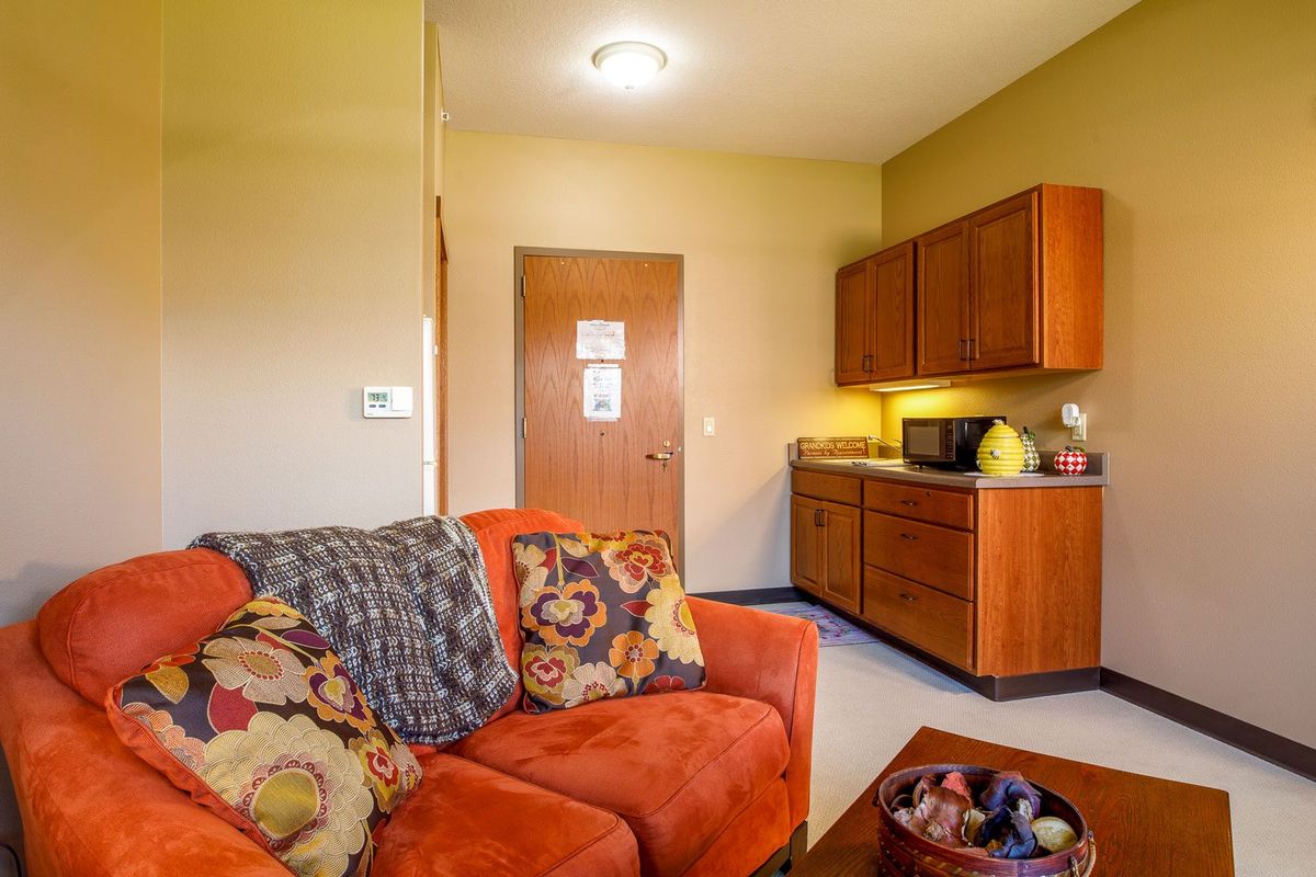 A cozy living area with a colorful sofa and a small kitchenette in the background.