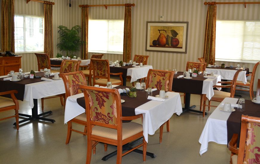 A tastefully decorated dining room with multiple tables and chairs, set for dining.