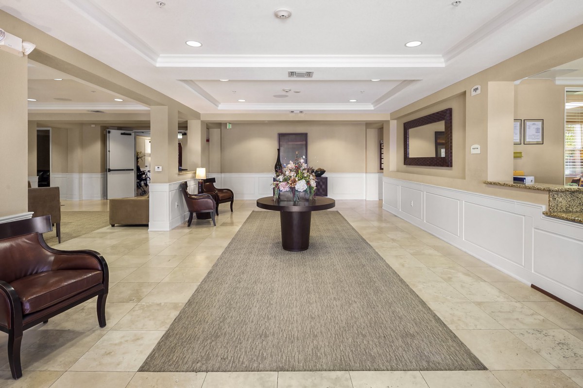 A spacious and elegantly decorated lobby area with comfortable seating and a centerpiece table displaying flowers.