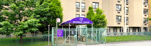 The entrance of the Bushwick Center, featuring its distinct purple awning and gated access.