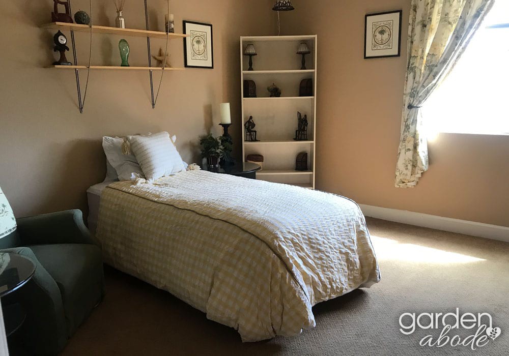 A cozy bedroom with a single bed, shelves, and decorative elements.