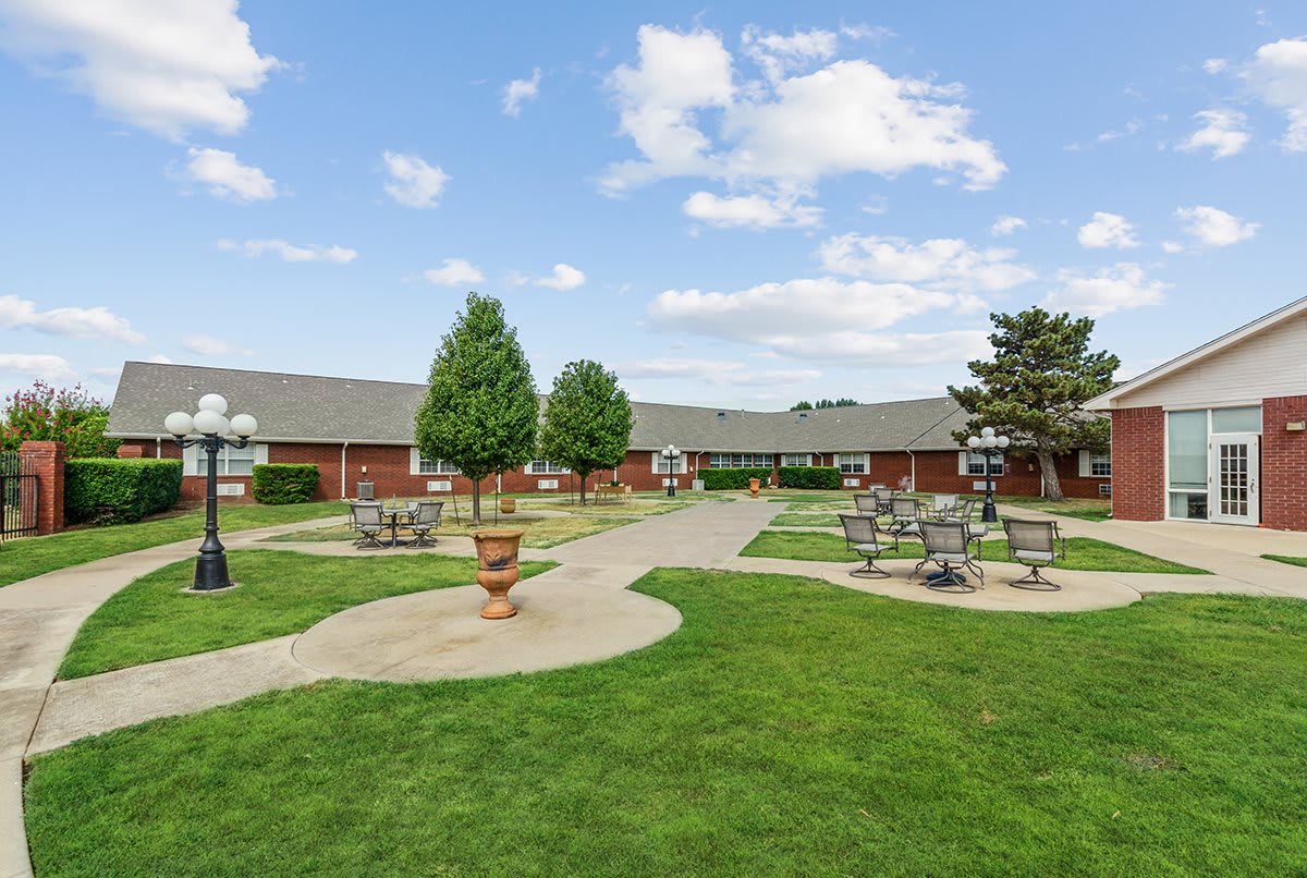 A landscaped courtyard with pathways, benches, and trees under a partly cloudy sky.