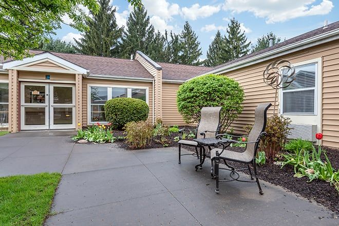 A cozy outdoor patio area with seating, surrounded by well-maintained landscaping and green bushes.