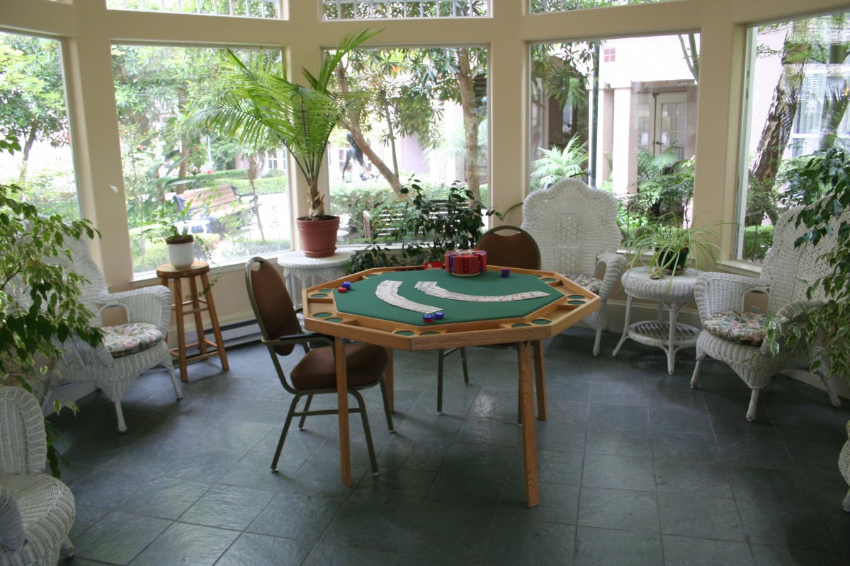 A cozy indoor setting with a poker table and chairs surrounded by potted plants.