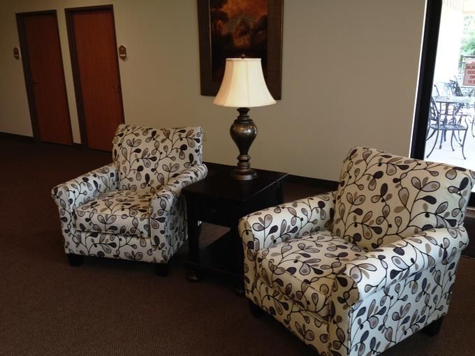 A cozy seating area with patterned chairs and a central lamp.