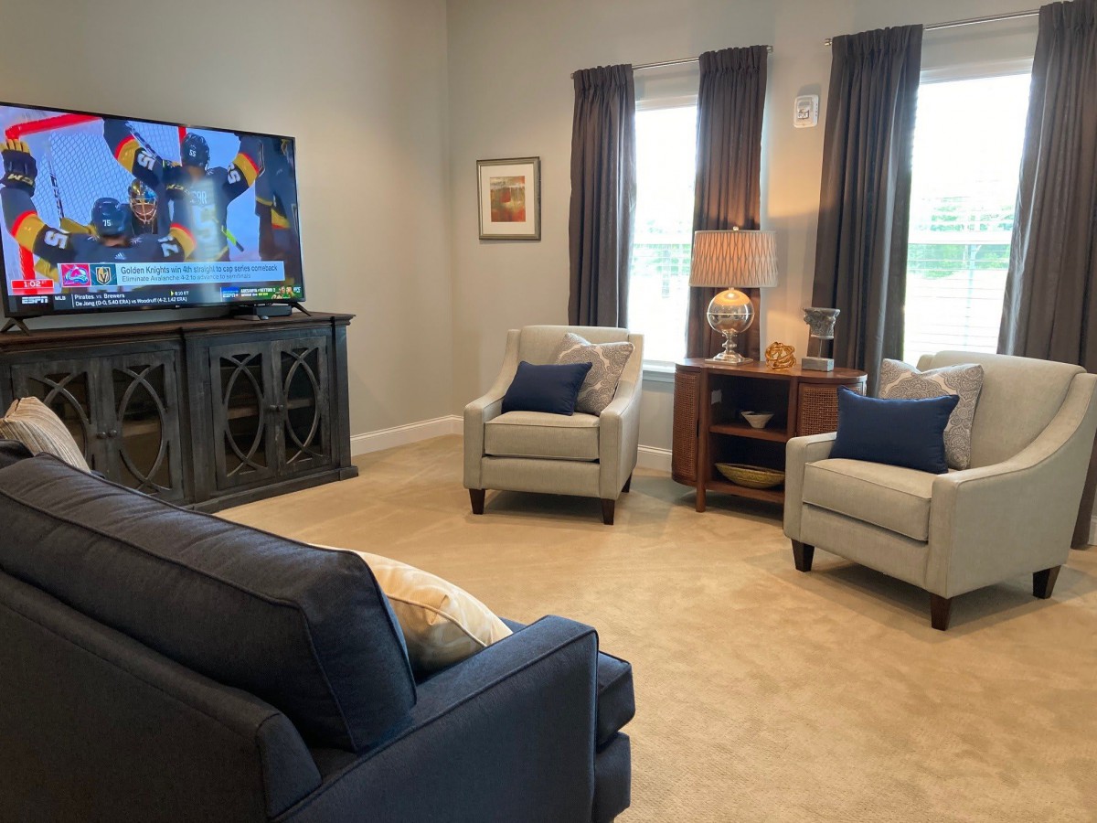 A cozy living room with a television, two armchairs, a sofa, and elegant decor.