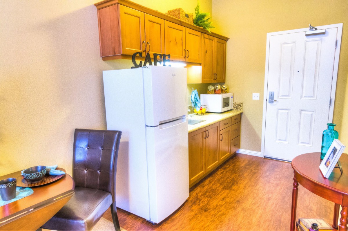 A compact kitchen area with a fridge, microwave, and wooden cabinets.