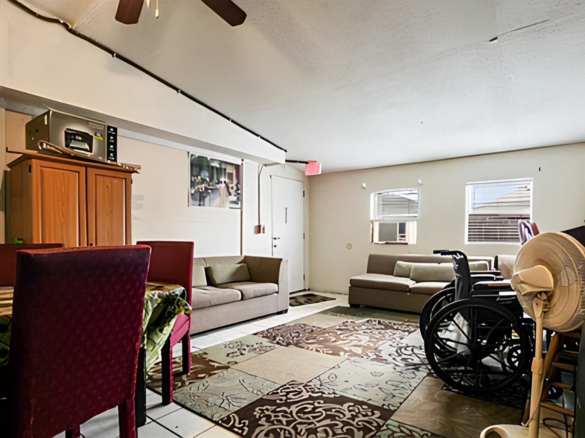 A cozy living room with sofas, a wheelchair, and decorative rugs.