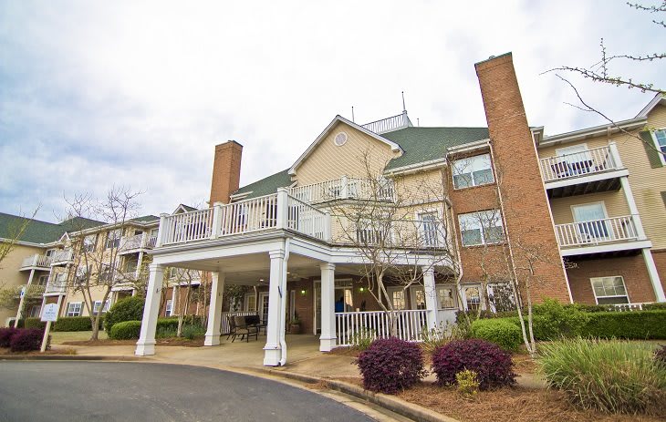 A large residential building with a covered entrance and landscaped surroundings.