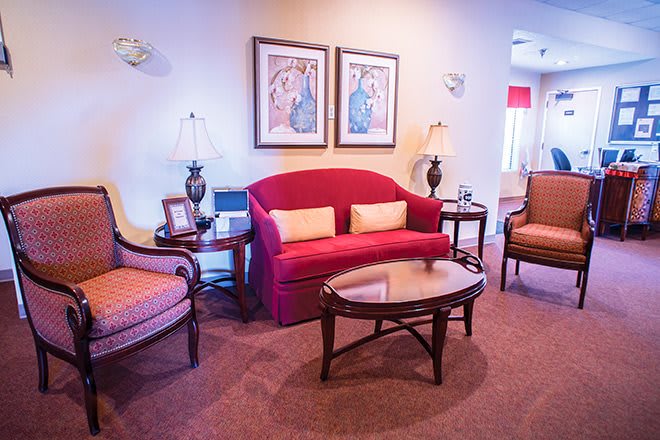 A cozy living room with a red sofa, matching chairs, and elegant decor.