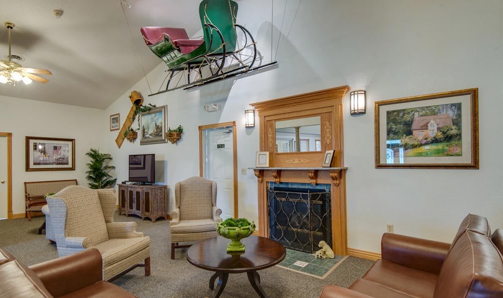 A cozy living room with vintage decor and a sleigh displayed above the fireplace.