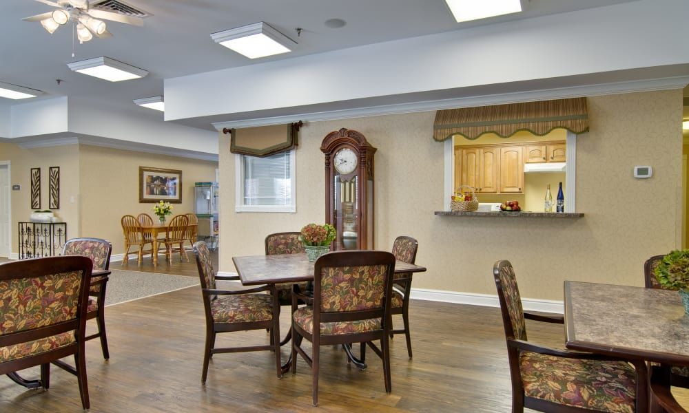 A cozy dining area with a table and chairs, adjacent to a kitchen, featuring a wooden floor and a grandfather clock.