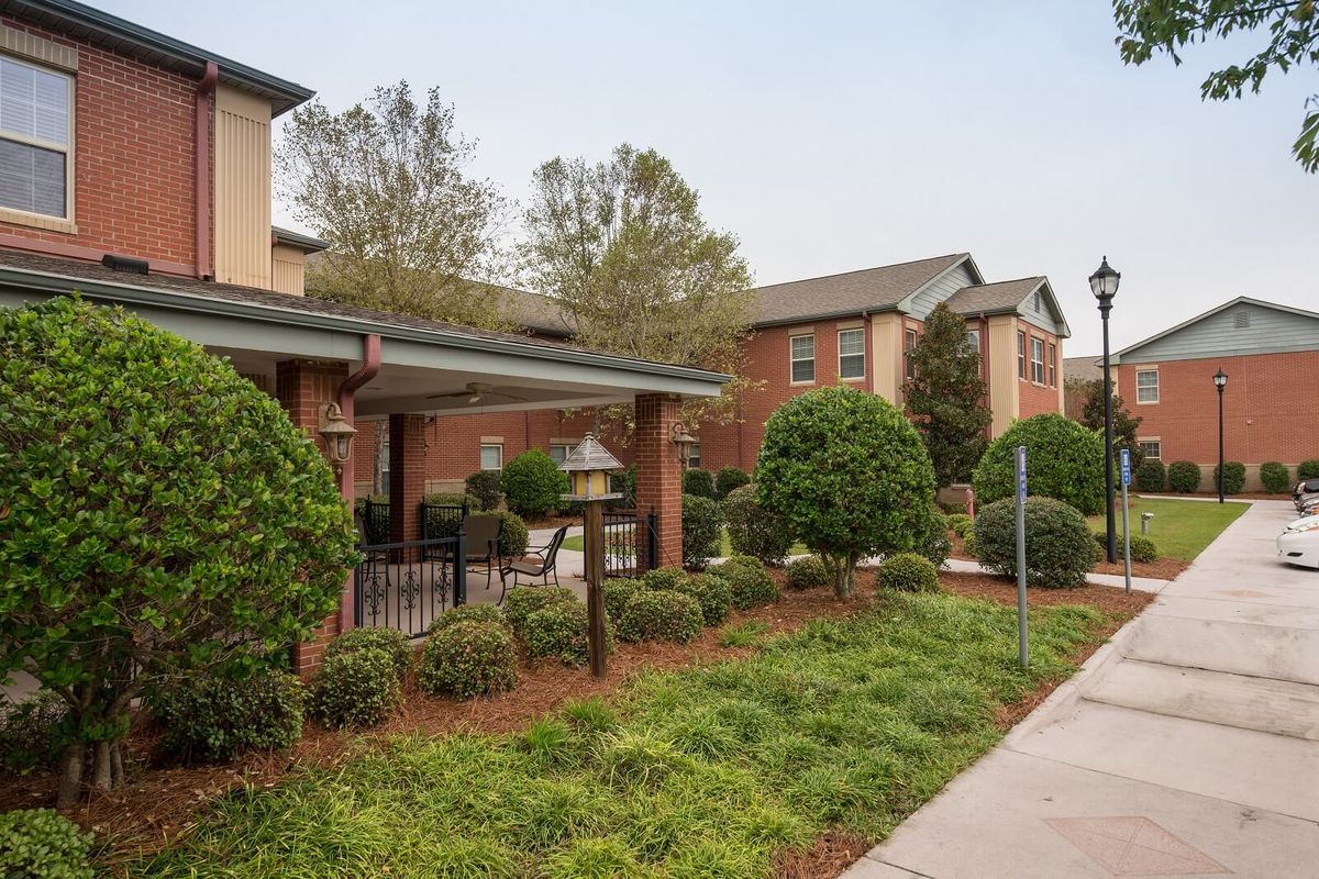 A well-maintained building surrounded by lush greenery and a tidy pathway.