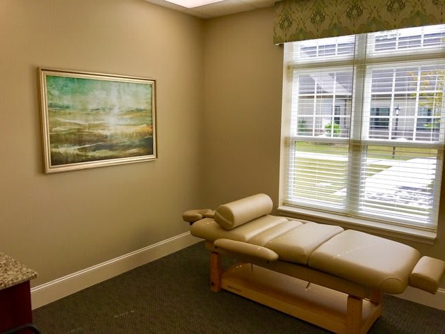 A serene therapy room with a massage table and a large window.