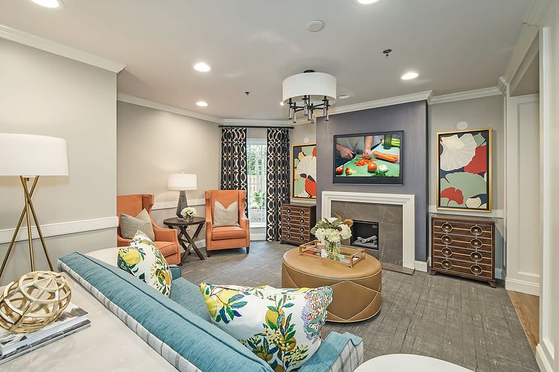 A modern living room with vibrant decor, featuring a sofa, chairs, and a fireplace.