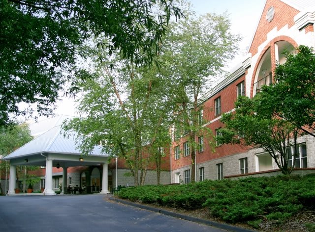 A brick building with trees lining its entrance.