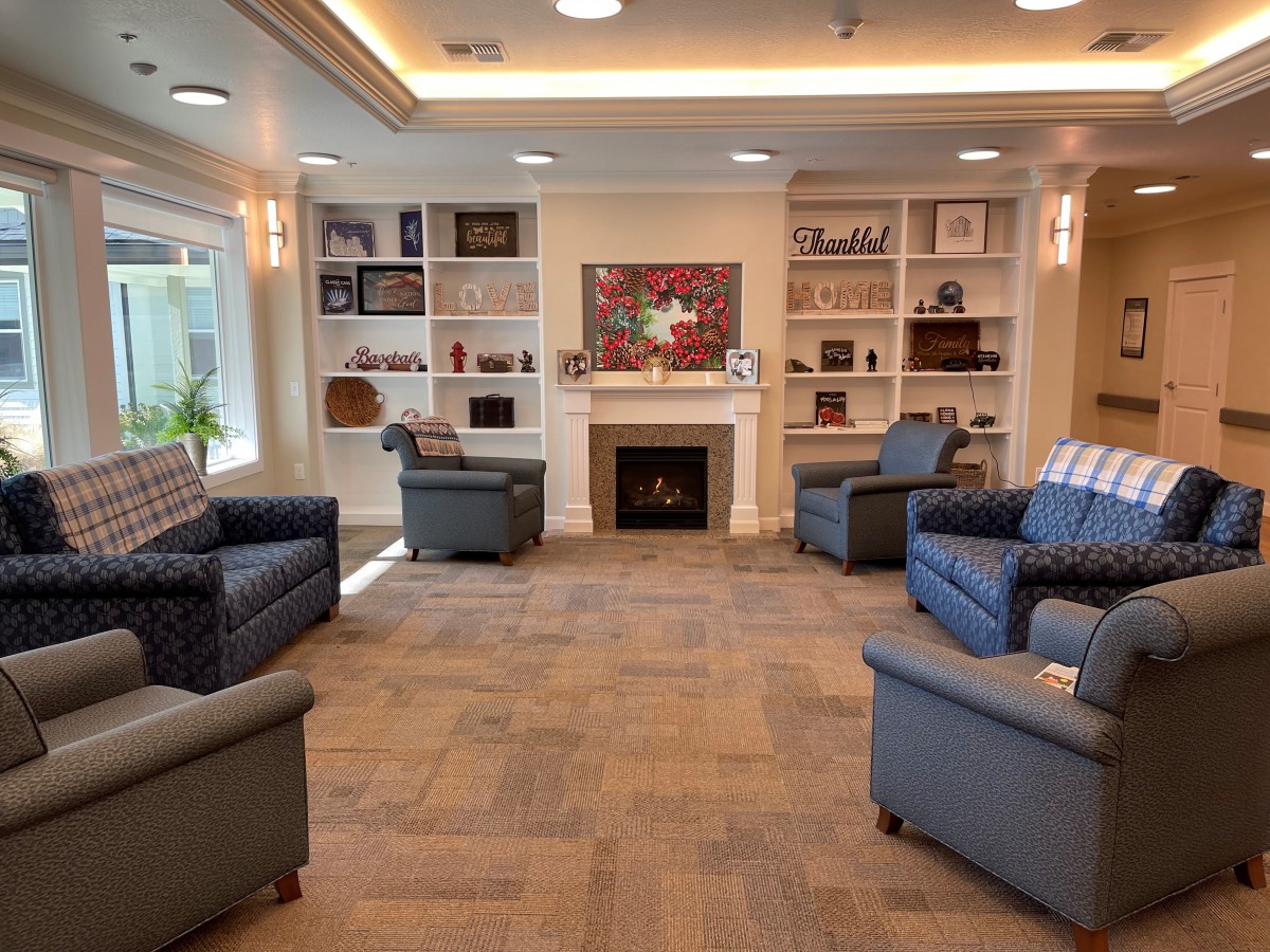 A cozy living room with comfortable seating, a fireplace, and decorative shelves.