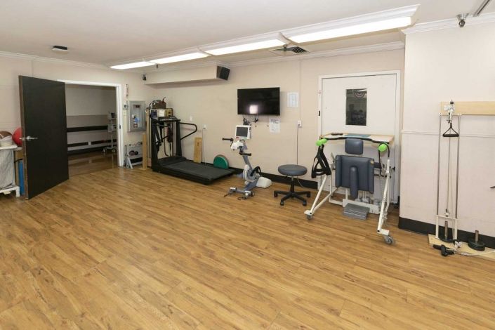 A small fitness room equipped with a treadmill, stationary bike, and other exercise machines.