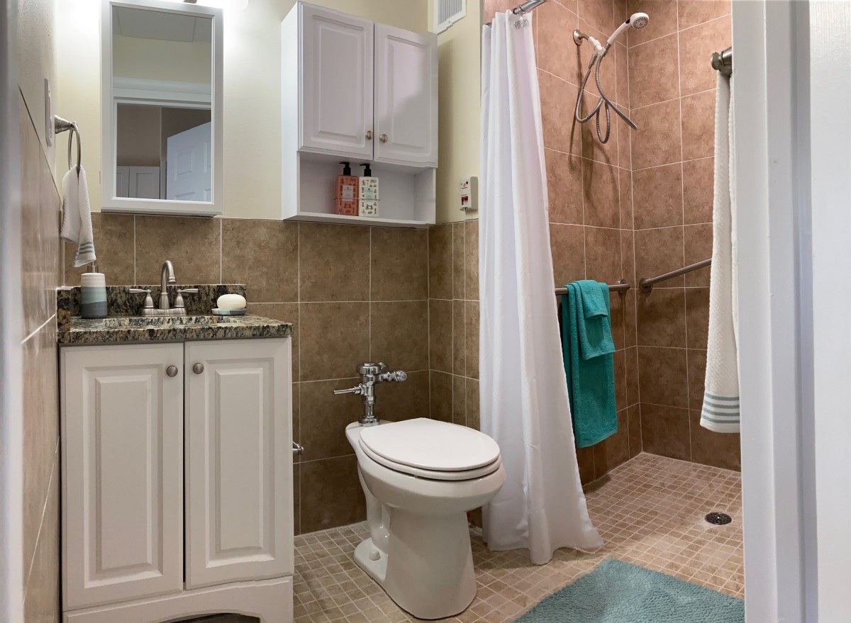 A modern bathroom with a toilet, sink, shower, and cabinet.