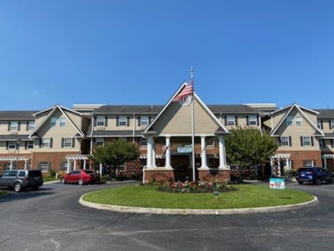 A well-maintained building with a flagpole and surrounding greenery under a clear blue sky.