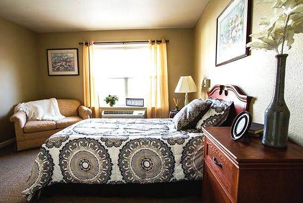 A cozy bedroom with patterned bedding and natural light streaming through the window.