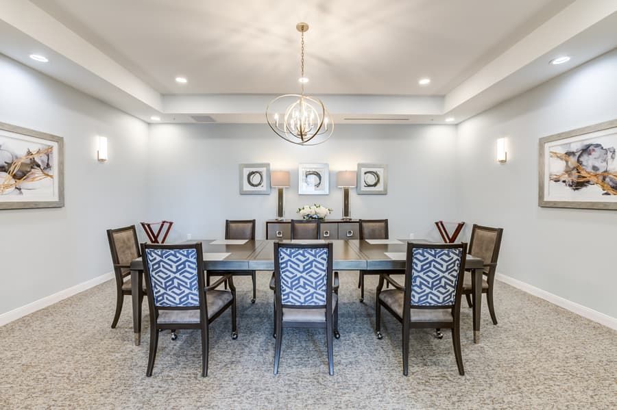 A spacious dining room with a large table and elegant chairs, complemented by a modern chandelier and wall art.