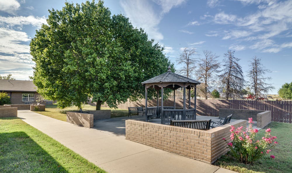 A peaceful park setting with a gazebo surrounded by trees and benches.
