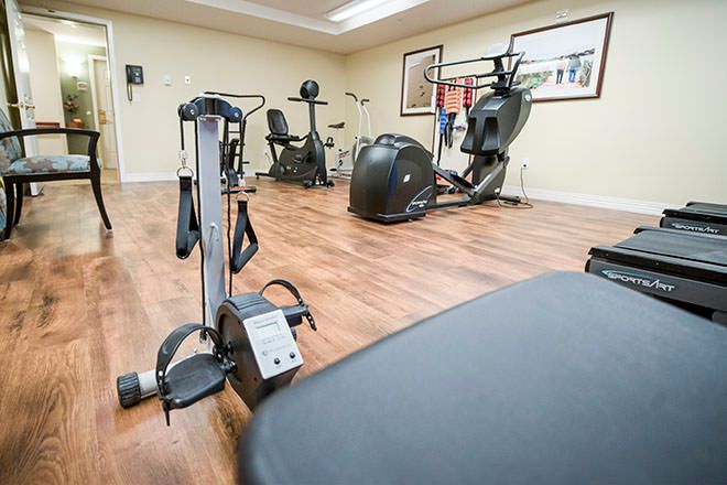 A well-equipped gym with various exercise machines, including a rowing machine and elliptical trainer.