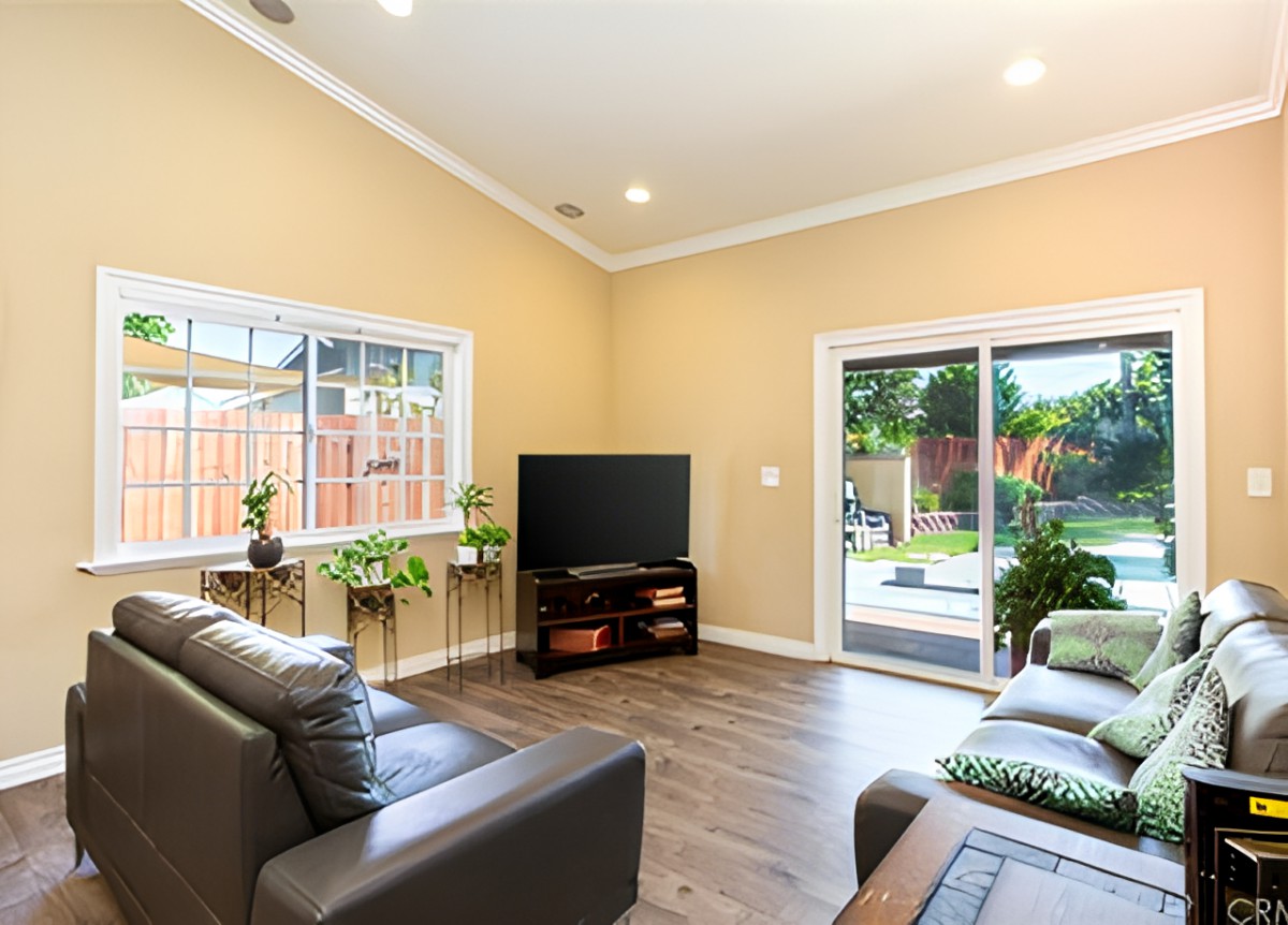 A modern living room with comfortable sofas, a television, and natural lighting from large windows and a sliding door.