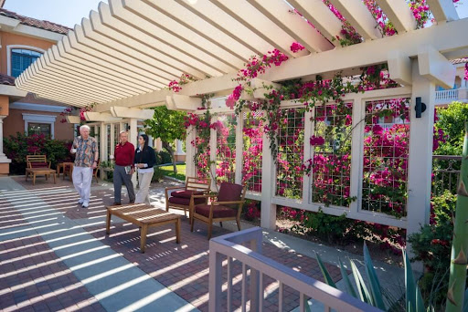 A serene outdoor space adorned with vibrant flowers, featuring a pergola and comfortable seating.