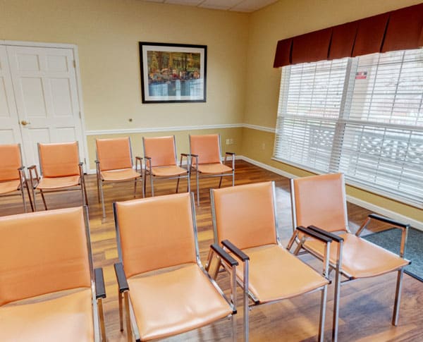 A small meeting room with neatly arranged chairs and a large window.