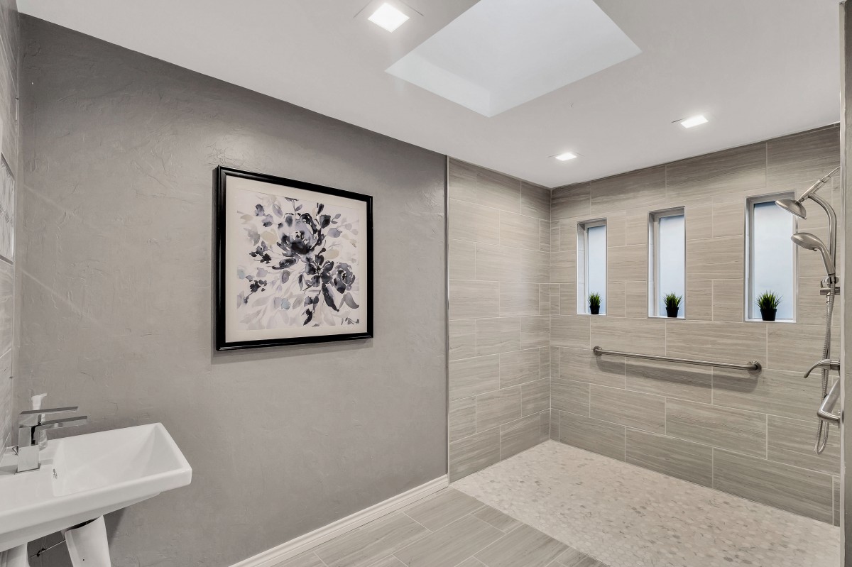 A modern, minimalist bathroom featuring a walk-in shower with recessed lighting and elegant tile design.