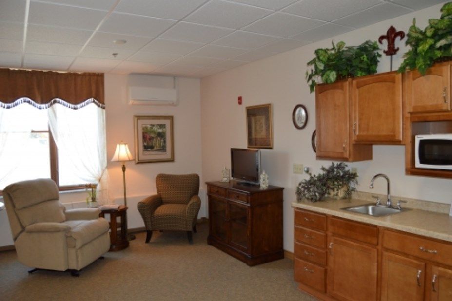 A cozy living area with an armchair, sofa, television, and kitchenette.