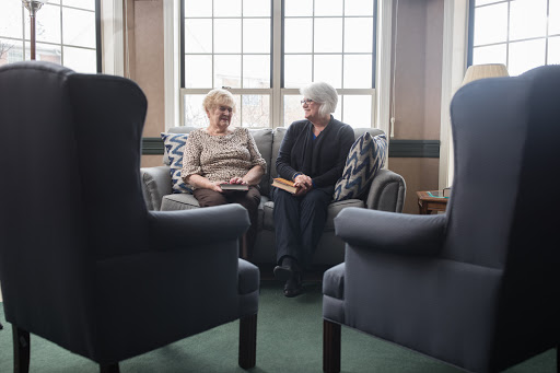 Two seniors engaged in a heartfelt conversation on a cozy couch.