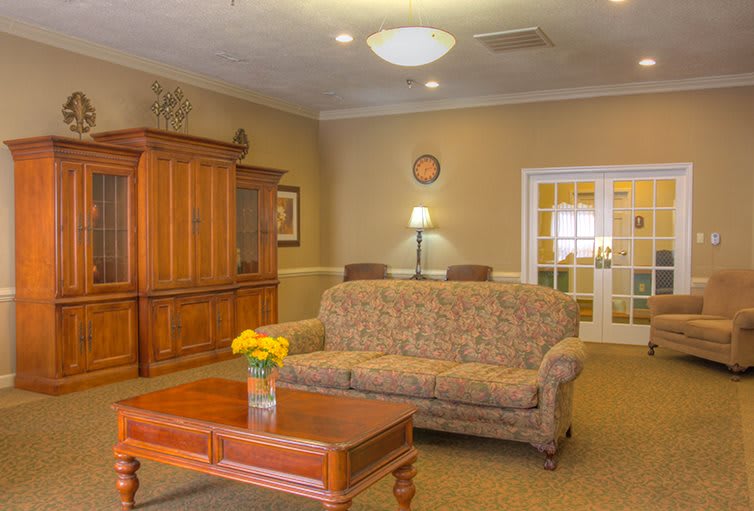A cozy living room with a sofa, wooden cabinet, and a coffee table adorned with flowers.