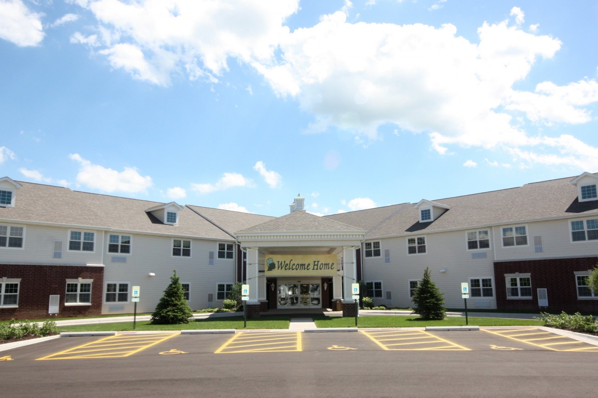 A two-story building with a parking lot in front, set against a partly cloudy sky.