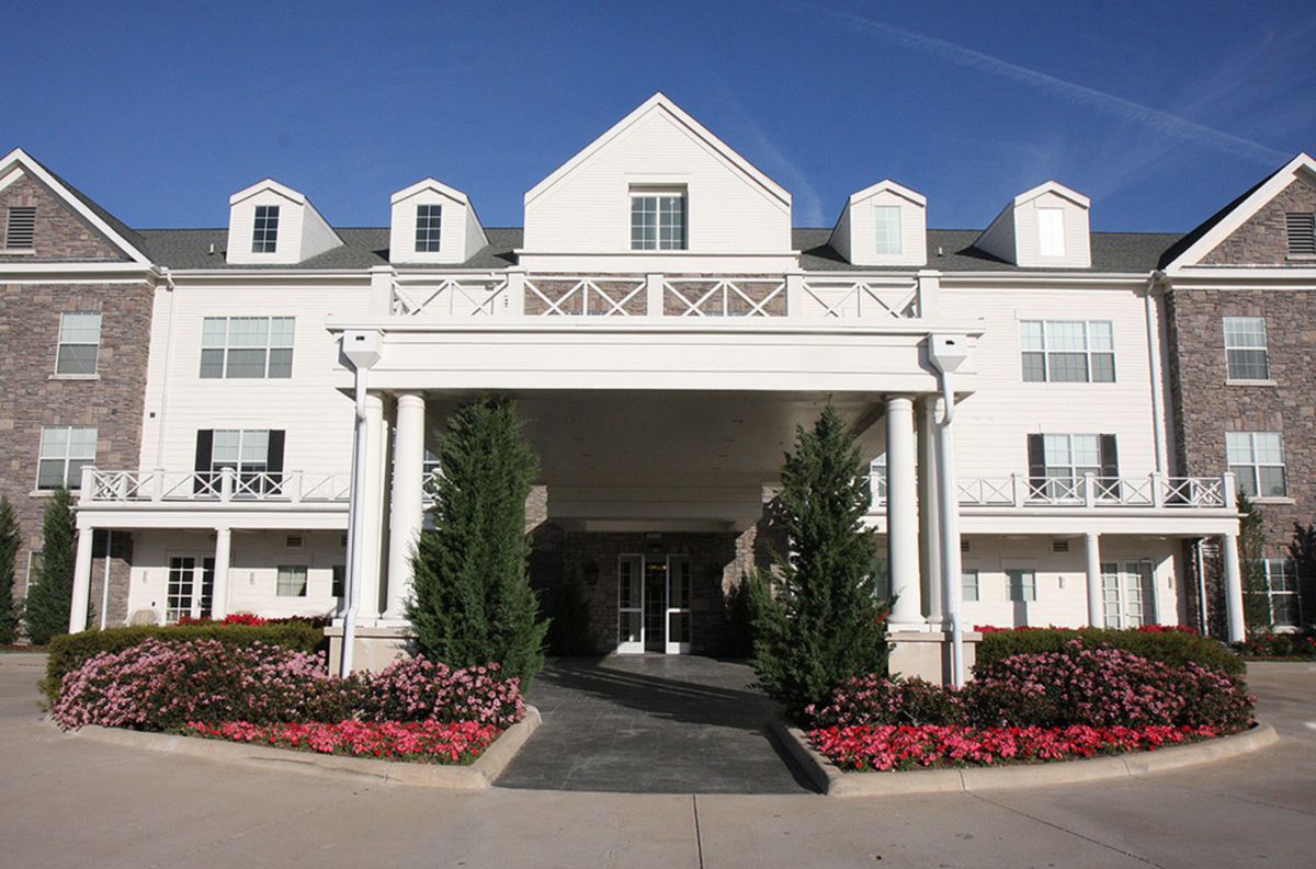A grand entrance with white columns and landscaped flower beds.