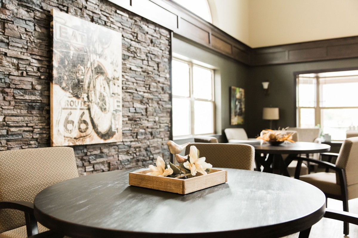 A modern lounge area featuring a round table, stone accent wall, and stylish decor.