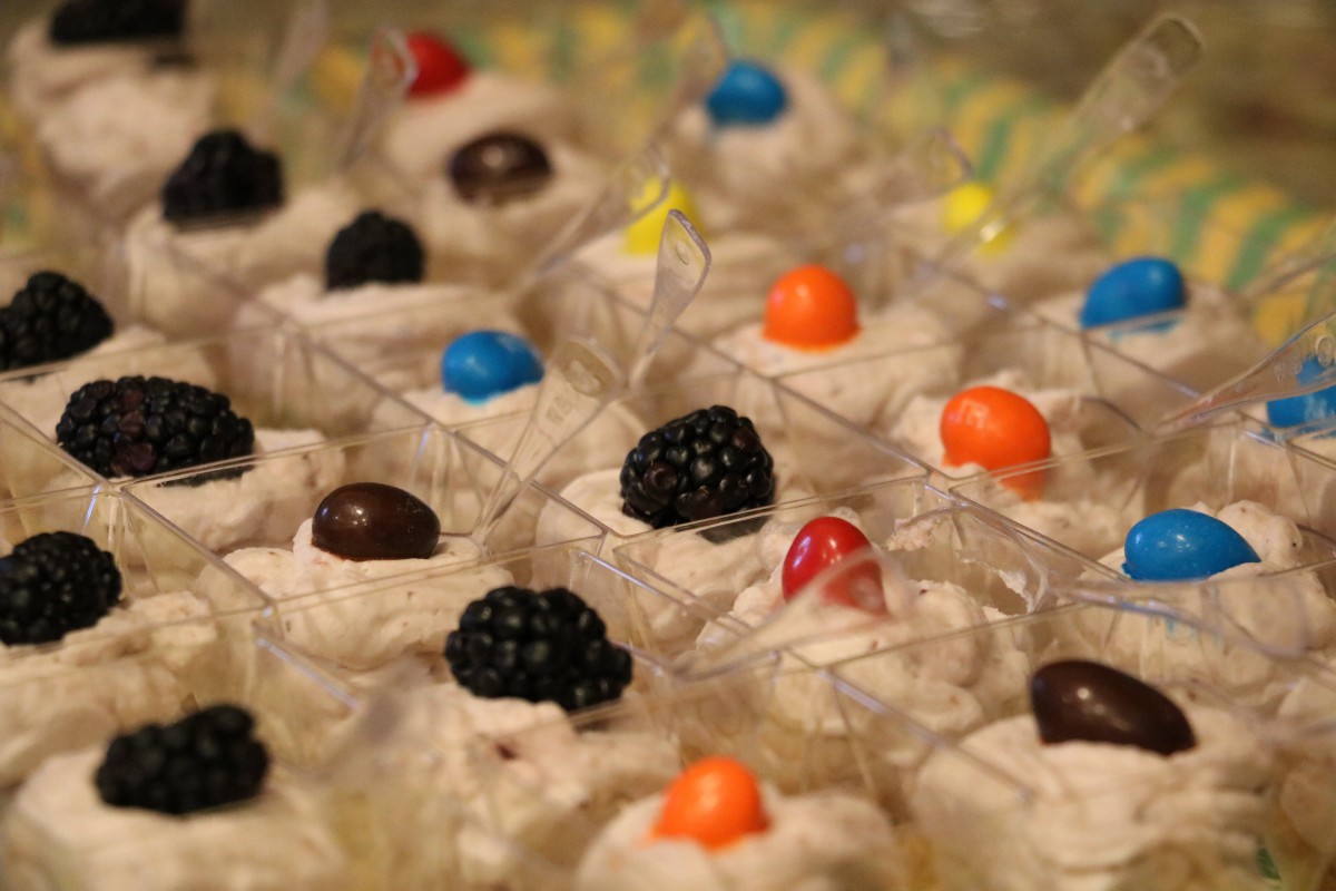 A selection of creamy desserts adorned with vibrant candies and fresh berries.