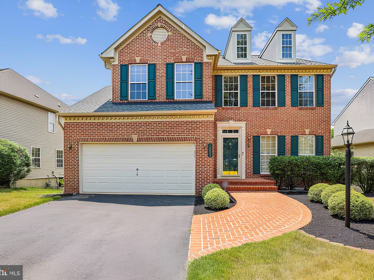 A suburban brick house with a two-car garage and landscaped front yard.