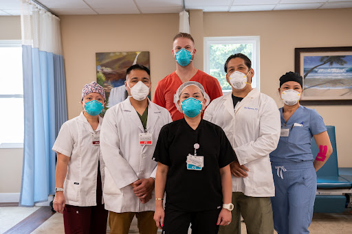 A dedicated healthcare team posing together in a medical facility, showcasing their commitment and protective measures during the pandemic.