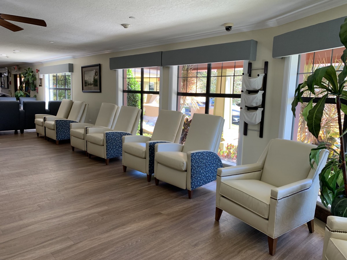 A row of comfortable chairs in a bright waiting area with large windows.